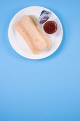 Sticker - Vertical shot of ladyfinger cookies on a plate with ketchup dip isolated on blue background