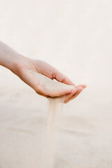 White sand pours through the fingers.