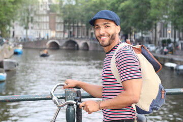 Wall Mural - Young mixed race man enjoying a European cityscape view with a river 