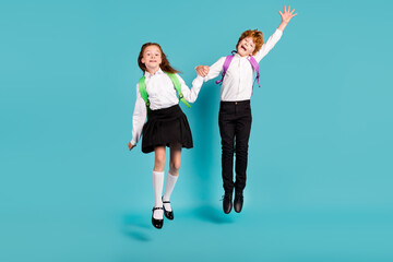 Poster - Photo of two funky dreamy kids jump go school wear rucksack white shirt uniform isolated blue color background