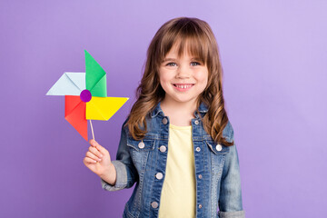 Wall Mural - Photo of cheerful playful little girl hold propeller toy wear jeans jacket isolated violet color background