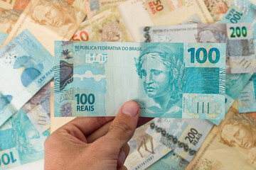 Wall Mural - Brazillian Money, man holding 100 Reais notes