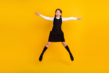 Wall Mural - Full length body size photo schoolgirl in uniform jumping up happy isolated bright yellow color background