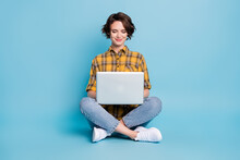 Photo Of Charming Freelancer Lady Sit Floor Typing Netbook Wear Plaid Shirt Jeans Shoes Isolated Blue Color Background