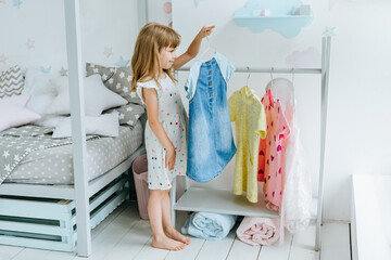 Wall Mural - beautiful little girl choosing a dress in the kids room