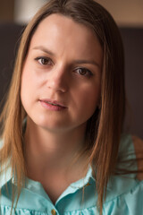 Wall Mural - Portrait of a young beautiful brown-haired woman with long hair indoors on a dark background.