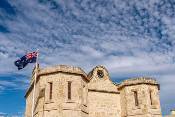 Detail of the historic prison in Fremantle, Western Australia, with the Australian flag blowing in the wind against a dramatic sky