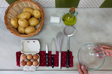 two hands setting the ingredients to make a potato omelette