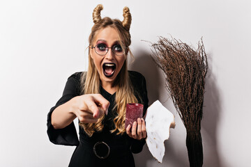 Wall Mural - Funny white witch in glasses laughing to camera. Good-humoured vampire posing in studio in halloween.