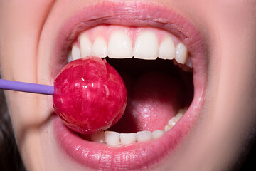 Wall Mural - Sexy red lips with candy for print. Red sweet lollipop in the mouth in art design. Glossy womans lips licking sucking lollipop. Sensual sexy mouth with candy concept enjoyment beautiful female lips.