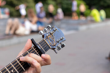 hand close-up taking a chord on an acoustic guitar outdoors