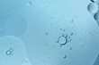 © kaedeezign - oil drop floating or Cosmetic liquid serum on the water blue bubbles background