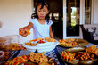 © Carlos David - Young Mexican latinx girl helping serving mexican style chips on plates for a party