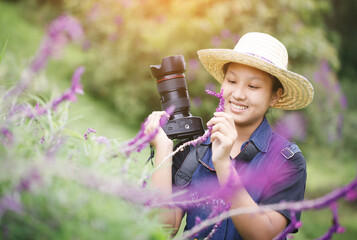 Smiling lifestyle portrait of pretty young girl taking pictures of flowers with lens camera