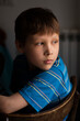 Portrait of a serious boy, sitting by the window. Selective Focus
