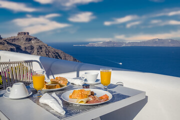 Breakfast table romantic view under idyllic blue sky sea. Perfect luxury breakfast food table for two outdoors. Amazing caldera view on Santorini, Greece, Europe. Summer vacation, honeymoon holiday