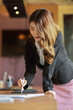 © bongkarn - Businesswoman lean on office desk and write on digital tablet