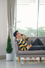 Wall Mural - Man on the phone while sitting on his sofa against a white background