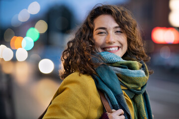 Fototapete - Smiling woman on city street during evening