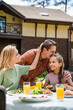 © LIGHTFIELD STUDIOS - Man kissing smiling daughter near wife and food outdoors