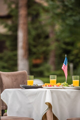 Wall Mural - American flag near food and orange juice on table outdoors