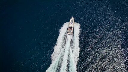 Wall Mural - aerial view of a luxury yacht traveling over blue sea leaving a trail of white waves and bubbles beh