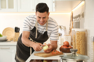 Canvas Print - Man peeling onion at kitchen counter. Preparing vegetable