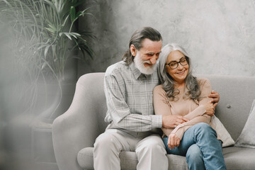 Wall Mural - Senior couple in casual clothes sitting on couch in living room