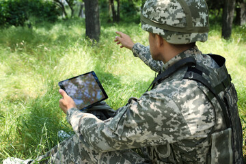 Wall Mural - Soldier with backpack using tablet in forest