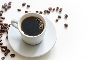 Poster - Top view closeup of a black and strong coffee in a white cup on a bright table with some beans