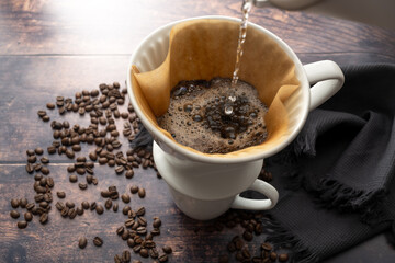 Poster - Top view closeup of a black and strong coffee in a white cup on a bright table with some beans