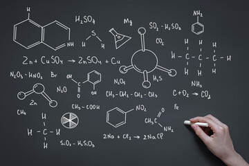 Sticker - hand with chalk draws on the blackboard formulas and elements, signs and symbols of chemistry, the concept of the study of substances, organic chemistry