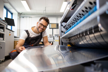 Wall Mural - Print worker working on computer to plate machine in printing shop.