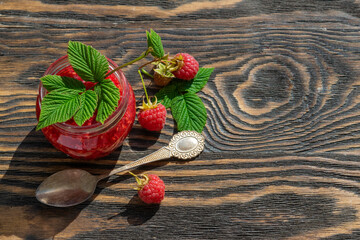 Wall Mural - Red ripe raspberries. Homemade raspberry jam in a glass jar on a wooden white table, selective focus, a copy space
