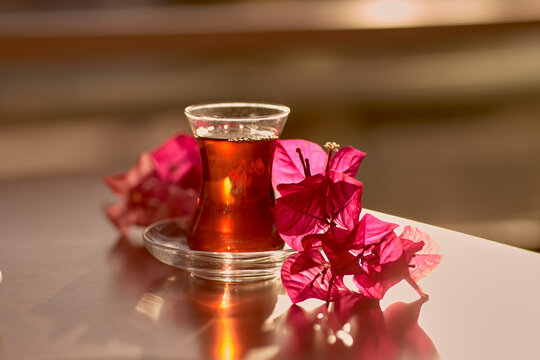 Turkish delight and traditional glass of turkish tea with bougainvillea flowers. Romantic dinner concept. Relaxing, calming drink Travel Turkey concept. Bright relaxing drink