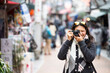 © Cavan Images - woman taking a picture with digital mirrorless camera in Tokyo