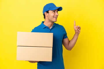 Delivery man over isolated yellow wall pointing up a great idea