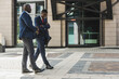 © xartproduction - Two dark-skinned african american businessmen in suits and glasses walk outdoors in the city and discuss business