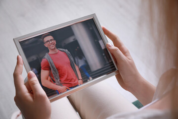 Sticker - Woman holding framed photo of happy man indoors, closeup