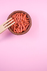 Wall Mural - Vertical shot of macaroni with a fork on a light pink background