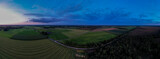 Fototapeta Sport - Blue hour aerial 180 degrees panorama of Dutch farmland landscape with colorful sunset in the sky. Agriculture farmland food industry.