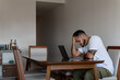 © Fabrizio - young latin tattooed man in front of laptop stressed out and holding his head
