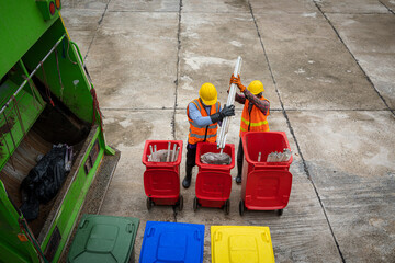 Wall Mural - Rubbish cleaner man working with green garbage truck loading waste and trash bin at city,Waste collectors at work,Top view.