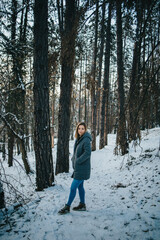 Sticker - Vertical shot of an attractive Caucasian woman with blond hair in the park during the winter