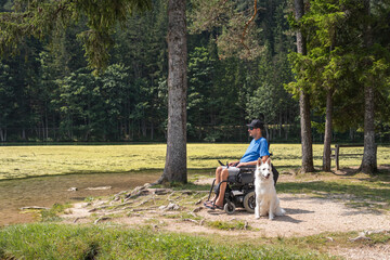 Wall Mural - Disabled man on wheelchair with his dog on a trip in nature.