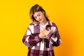 Wall Mural - Young Russian woman isolated on yellow background having a pain in the heart