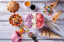 .Three Flavors Of Ice Cream In A Delivery Container, Making A Composition With Several Cones And Colored Gums. Top View