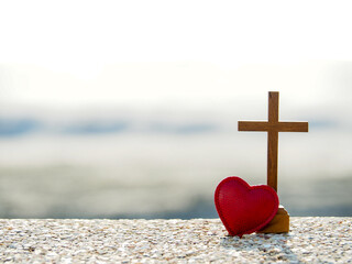 Wall Mural - Wooden  Christian cross and red heart against morning light on sea.