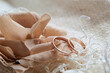 Gold wedding rings and a decorative flower made of dark beige fabric on a white mesh fabric. Close-up.