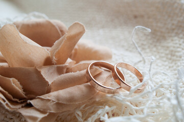 Wall Mural - Gold wedding rings and a decorative flower made of dark beige fabric on a white mesh fabric. Close-up.